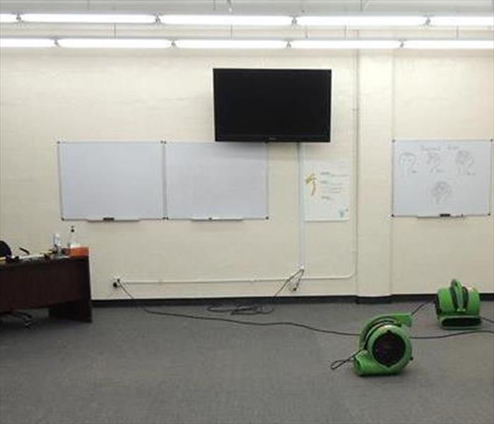 cleared floor, air movers drying carpet, desk off to side