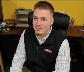 employee sitting at desk, black vest