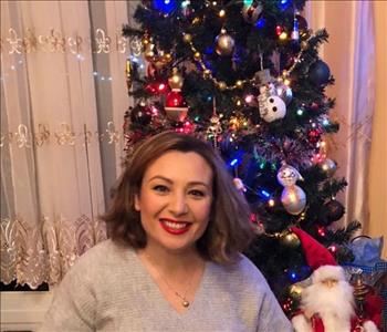 female employee posing in front of Christmas tree