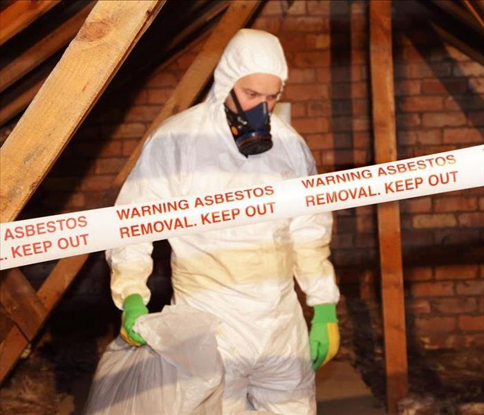 tech in white Tyvek suit removing asbestos