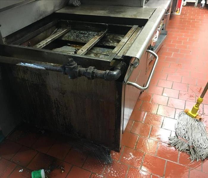 mopping floor of a commercial kitchen, greasy stove visible
