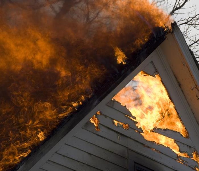Fire damage burning out of the top of a home.